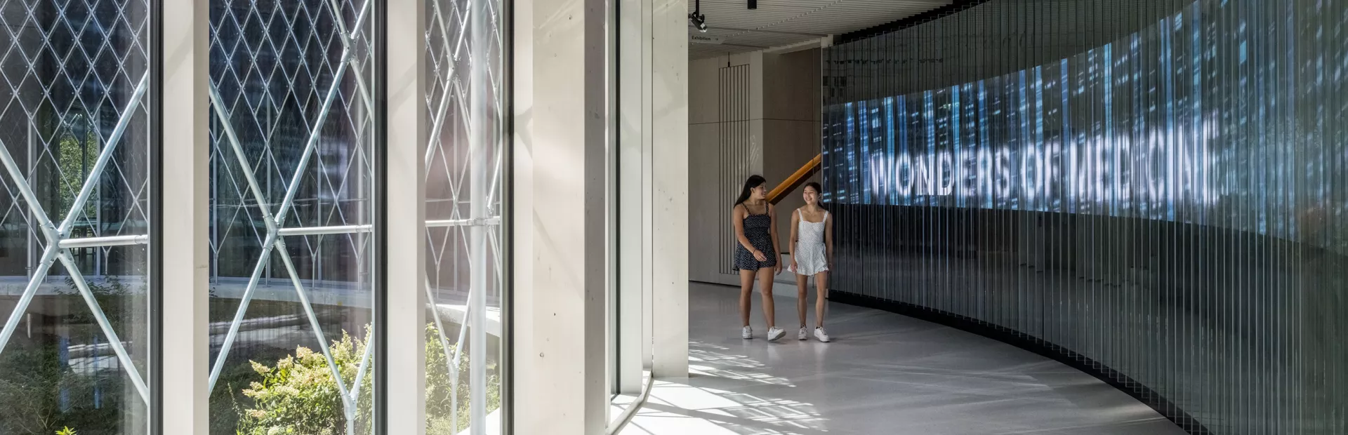 Two guests walking next to the welcome wall 