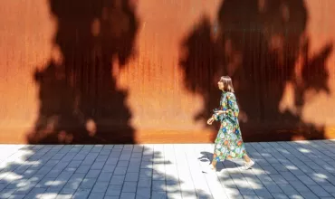 A woman walking past the high walls of the Dirk's Pod structure on campus