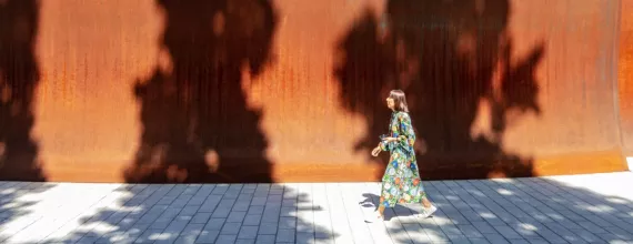 A woman walking past the high walls of the Dirk's Pod structure on campus