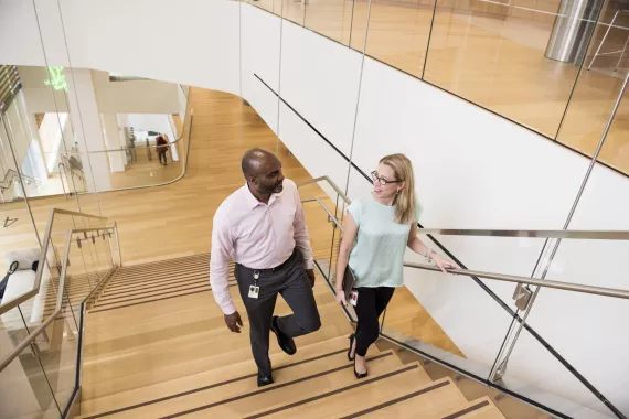 Two people in conversation walking up a wooden staircase