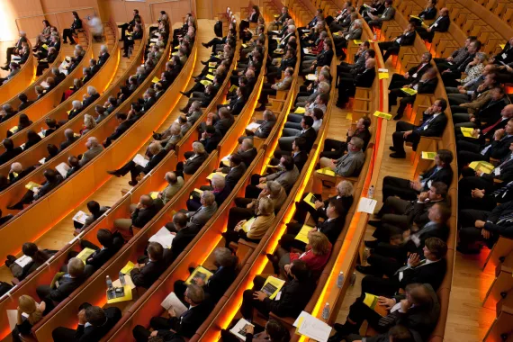 A crowd of seated people at a speaker event inside an auditorium